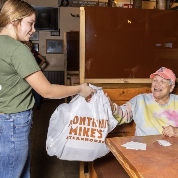 Montana-Mike's-guide-serving-customer-to-go-bag-close-up